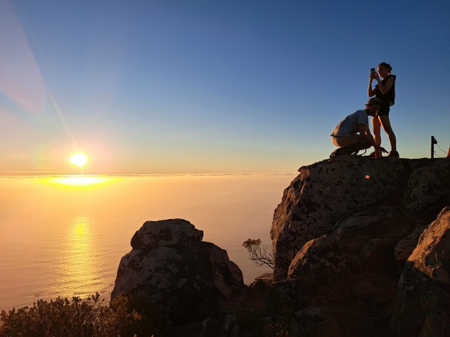 Two tourists enjoying sunset from the top of Lions Head