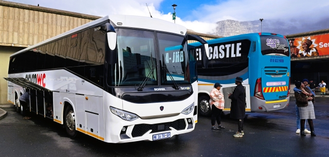 Couple embracing next to parked APMWC and Eagliner buses at the western side of Cape Town bus station