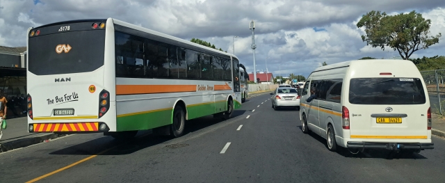 Golden Arrow bus moving into traffic with a minibus taxi in the next lane