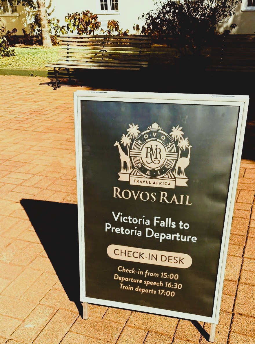 Sign saying Rovos Rail Victoria Falls to Pretoria Departure Check-in desk